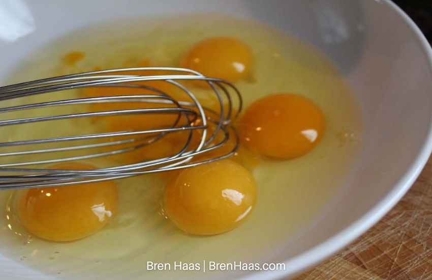 whisk fresh eggs in white bowl
